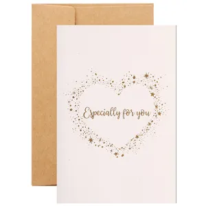 Elegante biglietto d'auguri bianco con cuore in oro e busta in carta kraft marrone.