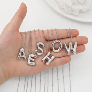 Gros plan détaillé du collier pendentif lettre argenté rebondi, bijoux alphabet.