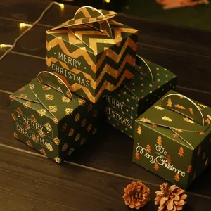 Set di quattro scatole regalo di Natale festive con manici su fondo in legno scuro