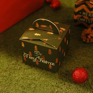 Scatola regalo di Natale verde scuro con motivo ad albero d'oro e auguri sull'erba