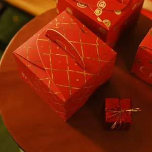 Scatole per confezioni regalo di Natale rosse e oro con motivi a rombi su tavolo di legno