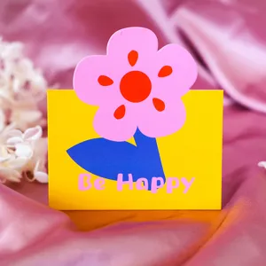 Biglietto d'auguri floreale con fiore rosa e scritta Be Happy su sfondo giallo brillante