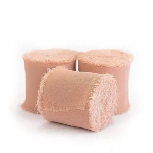 Makro-Detailansicht von drei handgefertigten staubrosa Chiffonbändern mit Fransenrand für DIY
