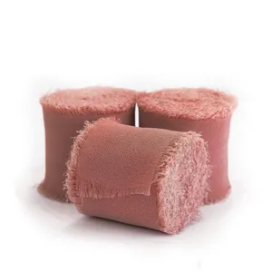 Nahaufnahme von drei Rollen staubrosa Chiffonband mit Fransen für DIY