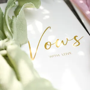 Elegant personalized wedding vow card with gold foil lettering and soft green ribbon.
