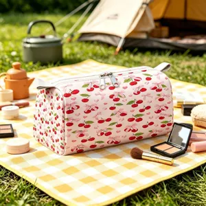 Close-up of pink velvet makeup bag with cherry and bow pattern in outdoor picnic scene