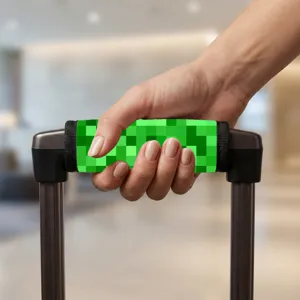 Nahaufnahme eines Koffergriffschutzes mit grünem Pixelmuster an einem Koffergriff.