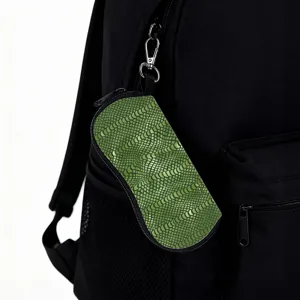 Macro view of green snakeskin eyewear pouch hanging from a black backpack