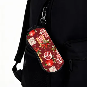 Detail view of the portable fruit print glasses pouch attached to a black backpack hook