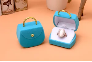 Detaillierte Ansicht der blauen Samt Handtasche Ringbox mit Ring, ideal Schmuckpräsentation.