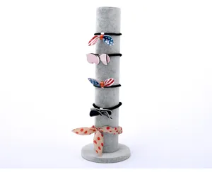Close-up view of a grey velvet vertical cylinder jewelry display stand showcasing stylish hair ties.
