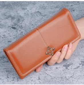Close-up of a women's brown leather long wallet with decorative metal flower emblem