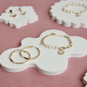 Primo piano dettagliato di eleganti orecchini a cerchio dorati e bracciali su base bianca.