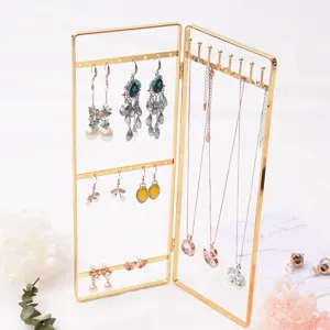 Gold folding jewelry display stand detail showing earring and necklace hanging hooks clearly.