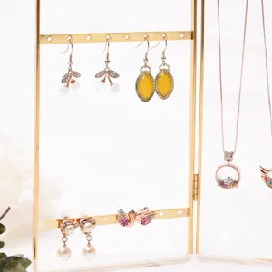 Detailed view of fashionable crystal swan and pearl earrings displayed on a gold jewelry rack.