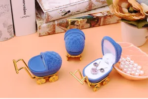 Blue velvet baby carriage jewelry box with golden metal wheels and handle, elegant ring gift case.