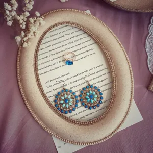 Gedetailleerde close-up van blauwe bloemoorringen in vintage stijl en bijpassende ringerset.