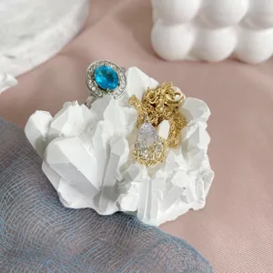 Prachtige kristallen druppelhanger ketting en elegante blauwe steen ring op witte prop.