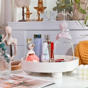 Detailed view of white rotating storage tray with jewelry stand and cosmetic bottles on table.