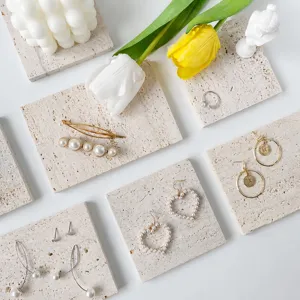 Travertine stone display tray prop and aesthetic fashion earrings for jewelry photography.
