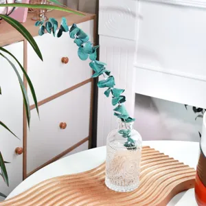Wooden wavy decorative tray with glass vase and eucalyptus branch for home interior styling.