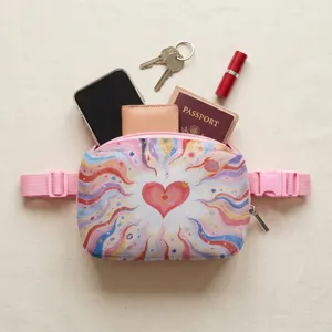 Lifestyle-Ansicht einer rosa Bauchtasche mit Herzprint und Reiseutensilien wie Handy und Pass.