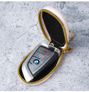 Detailopname van een draagbaar roze lederen autosleuteletui met gouden ritssluiting