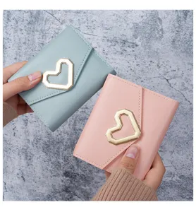 Detailed view of the gold heart buckle on pink and light blue faux leather wallets