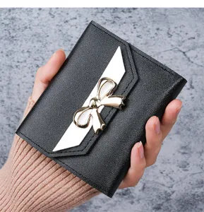 Elegant compact black women's wallet featuring a metallic bow and textured finish