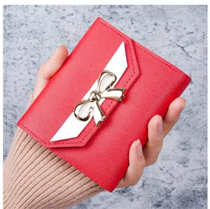 Detailed view of women's red leather short wallet featuring a white flap and golden bow-knot