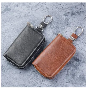 Close-up detail of premium black and brown leather key cases with metal carabiner clips.