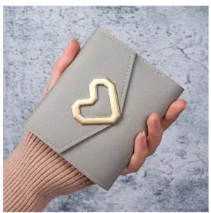 Detail of trendy grey wallet featuring a golden heart-shaped metal buckle and texture