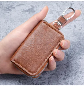 Detail of brown leather coin purse with zipper and metal keychain held in hand
