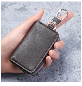 Close-up of a compact brown leather key pouch held in hand, showing metal clasp