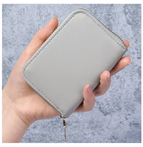 Porte-cartes gris en cuir texturé avec fermeture éclair dorée en forme de cœur.