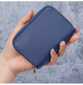 Gros plan d'un petit porte-cartes bleu marine en cuir avec une fermeture éclair dorée.
