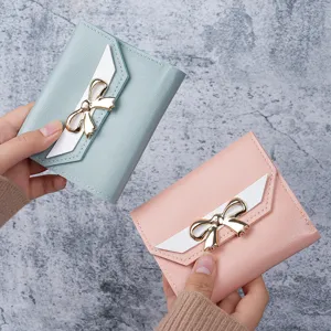 Elegant women's short wallet featuring a decorative golden bow in pastel pink and blue colors.