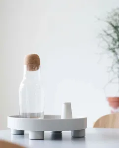 Minimalist white raised decorative tray with glass carafe detail for home decor and display.