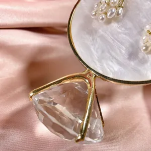 Gedetailleerde close-up van een creatieve sieradenstandaard met kristallen diamantvoet en parel.