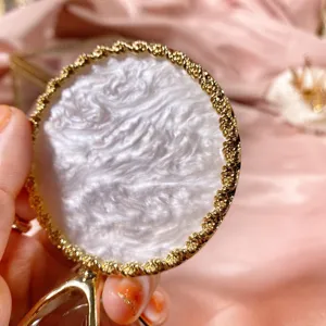 Rond decoratief sieradenplateau met parelmoerwitte textuur en elegante gouden rand voor fotorekwisieten.