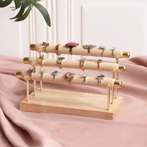 Three-tier solid wood ring display stand featuring beige velvet rolls for secure jewelry storage.