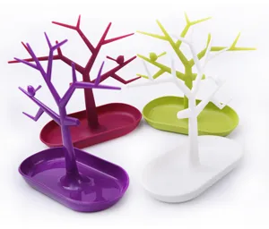 Tree branch jewelry stand detail, multi-color plastic organizer tray for rings and earrings.