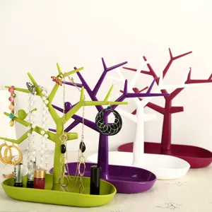 Creative plastic tree jewelry stand with tray for organizing necklaces, rings, and earrings.
