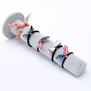 Set of 5 stylish bow hair ties and polka dot scrunchies displayed on a grey velvet stand.