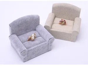Close-up detail of miniature sofa ring holders in grey and beige linen for jewelry display.