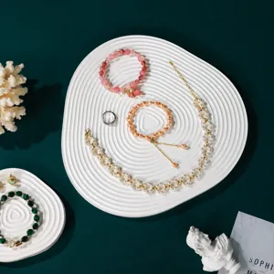 Elegant jewelry set with pearls and gemstone bracelets displayed on white wavy display trays.