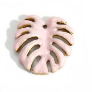 Primo piano dettagliato di un ciondolo a foglia di Monstera in smalto rosa e oro 18K