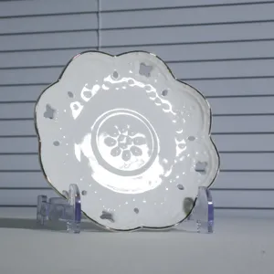 Witte keramische koffieschotel met geschulpte zilveren rand en delicate reliëf bloemmotieven.