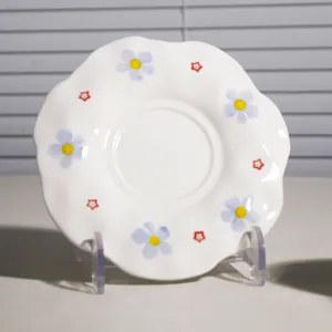 Platillo de café de cerámica con borde ondulado y tierno diseño floral para la tarde.