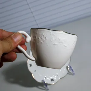 Witte keramieken koffiekop en schotel set met elegant reliëf patroon en gouden rand voor latte.
